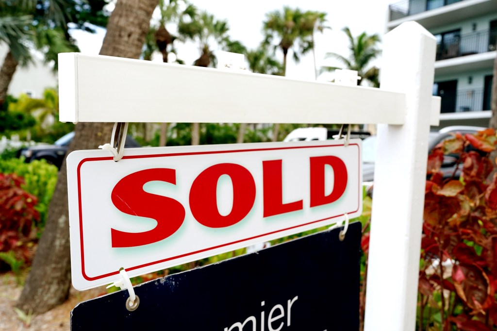 A sold sign displayed in front of a condominium building in Indian Shores, Florida, signifying a completed real estate transaction.